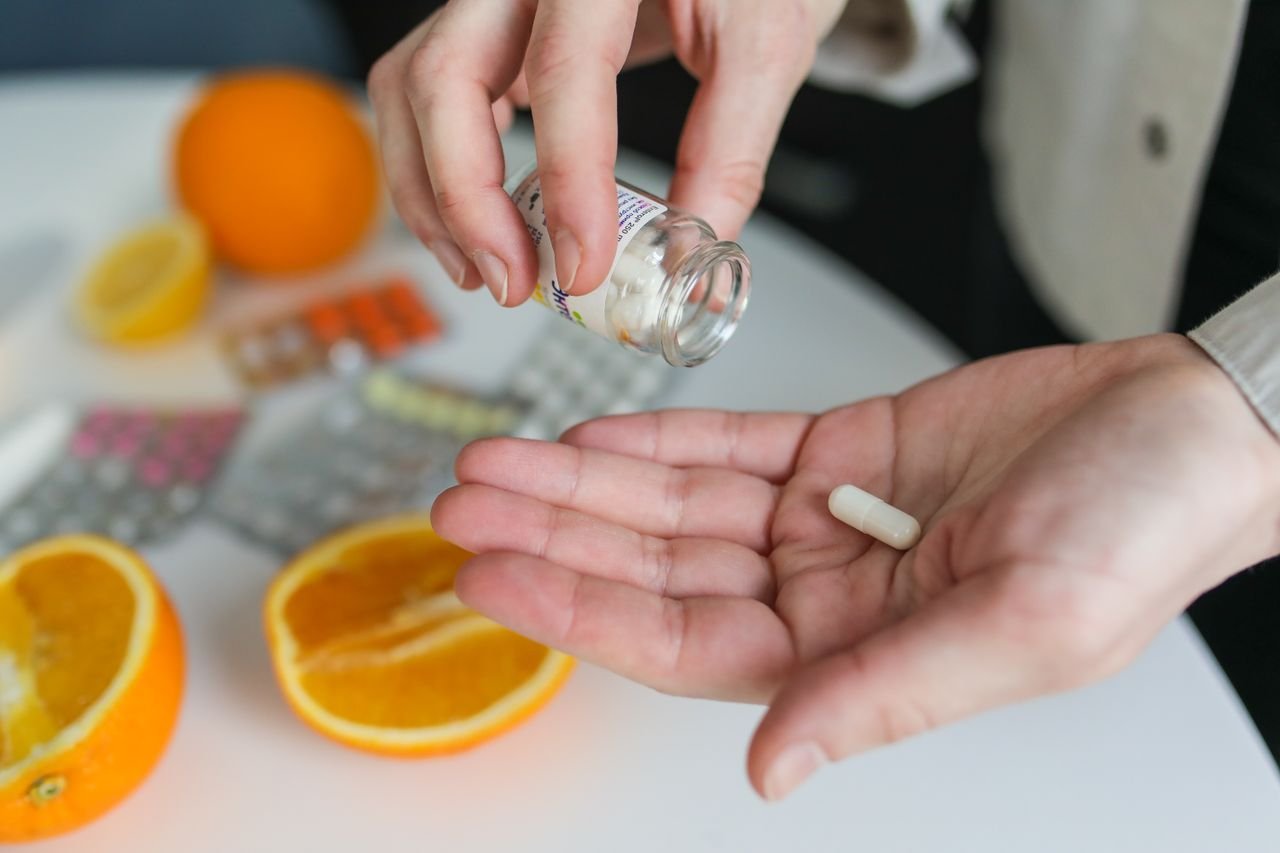 Mastering the First Impression: Your intriguing post title goes here Close-up of a person taking a vitamin capsule with citrus fruit and medication on a table.